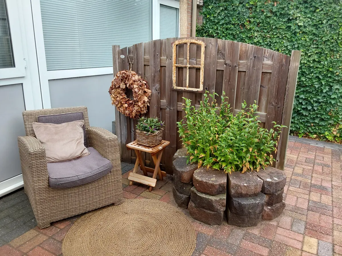 Beschut terras met stoel en planten bij Bij Kaatje Thuis