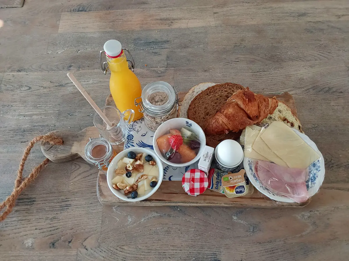 Verzorgd ontbijt met verse broodjes, fruit, yoghurt en sap bij B&B Bij Kaatje Thuis in Emmen